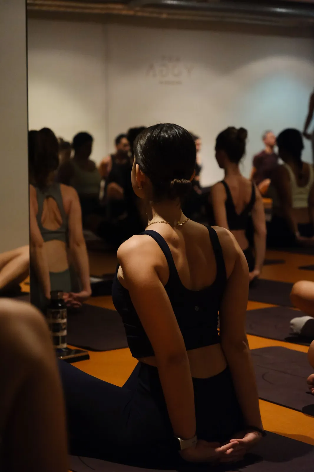 Asistentes sentados en sus esterillas durante una clase de yoga de After